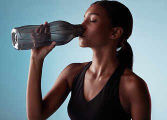 Image showing Fitness, sports and woman drinking water in studio for a healthy body after training, cardio workout and exercise. Wellness, blue background and thirsty girl enjoys a beverage to hydrate or hydration