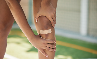 Image showing Woman athlete, knee pain and sport injury outdoor with bandaid with inflammation, joint and strain accident. Girl holding leg, muscles tear and joint swelling or muscle fatigue in sports competition