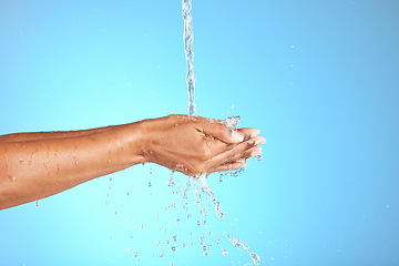 Image showing Hands, water and woman in studio for cleaning, washing hands and safety from bacteria against a blue background. Hand, splash and model washing for skincare, hygiene and germ prevention with mockup