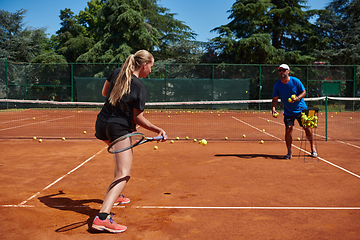 Image showing A professional tennis player and her coach training on a sunny day at the tennis court. Training and preparation of a professional tennis player