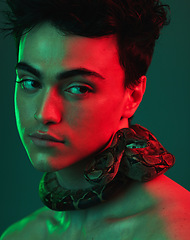 Image showing Beauty, snake and model in a studio with neon light of green and red color posing with a serpent. Skincare, face and man from Mexico standing with a reptile on his neck isolated by a green background