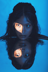 Image showing Beauty, woman and light on face reflection with mirror for edgy cosmetics, skincare or advertising. Shadow, thinking and spotlight on beautiful cosmetic black model with blue studio background.