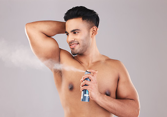 Image showing Deodorant, armpit and man spraying in studio for hygiene, wellness and self care. Spray, clean and young model from Colombia with fragrance with a fresh scent for grooming isolated by gray background