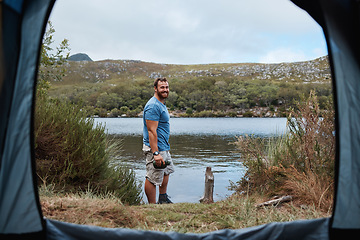 Image showing Man, camping and tent by lake, water or river stream in nature earth environment, countryside dam or America sustainability pond. Portrait, smile or happy hiker with flask on weekend adventure break