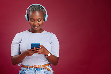 Image showing Smartphone, headphone and black woman in studio mock up listening, scroll and typing on music subscription streaming service. African girl using phone audio app on red mockup marketing or advertising