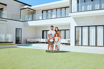 Image showing Family, children and real estate with a girl, parents and sister in the backyard of their home together. House, garden and property with a man, woman and kids standing on grass during the day