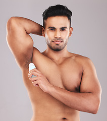 Image showing Deodorant, health and man cleaning armpit against a grey studio background. Wellness, care and portrait of a young model with an underarm product for grooming, clean skin and care for body hygiene