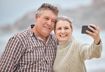 Image showing Phone, selfie and beach with a senior couple taking a photograph while on holiday or vacation travel together. Mobile, summer and retirement with a man and woman posing for a picture at the coast