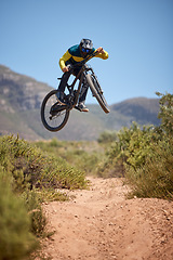 Image showing Bike, bmx and fitness with a man biker on a dirt trail or track taking a jump with a mountain bike. Sky, nature and cycling with a mountain biker jumping in midair while riding outdoor for adrenaline