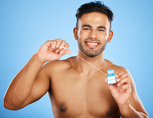 Image showing Floss, dental care and portrait of man on blue background studio for hygiene, health and cleaning teeth. Dental healthcare, healthy mouth and young model holding dental floss for morning routine