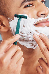 Image showing Shaver, foam and man shaving his beard for hygiene, health and smooth skin in a studio. Razor, clean and handsome guy from India grooming his facial hair for dermatology wellness or a face treatment.