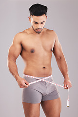 Image showing Weightloss, fitness and man with measure tape standing in a studio with a gray background. Health, strong and athlete with a healthy, exercise and diet lifestyle measuring his weight after a workout.