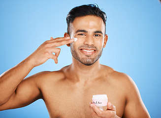 Image showing Beauty, skincare and man with cream on face for healthy skin on blue studio background. Moisturizer, lotion and young model from Canada hydrate with creme for body care, beautiful or glowing skin.