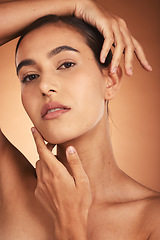 Image showing Portrait, skincare and beauty with a model woman touching her face in studio on a beige background. Hands, wellness and luxury with a female posing to promote a natural product or skin treatment