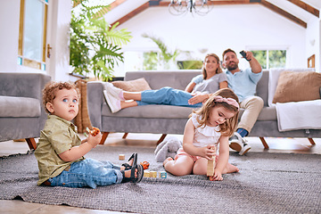 Image showing Parents on sofa, children play on floor in home and family time together on weekend morning in Dallas. Streaming movie, young kids bonding with toys and dad searching channel watching tv with mom