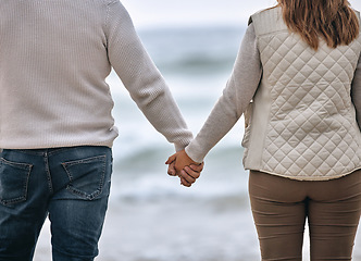 Image showing Couple, holding hands and beach in travel, love or romance for relationship bonding in the outdoors. Hands of man and woman in trust, support or care on romantic walk or trip by the ocean water