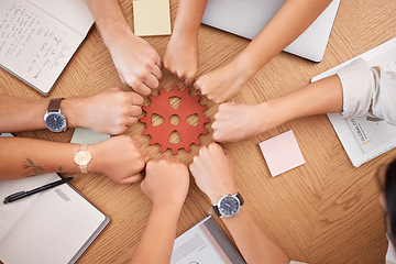 Image showing Hands, collaboration and gear with a business team working together at a table in the office from above. Teamwork, planning and synergy with a man and woman employee group in a huddle or circle
