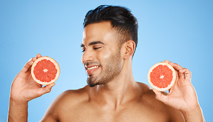 Image showing Man, face and grapefruit healthy skincare wellness glow vitamins. Young person model happy smile, luxury orange fruit beauty lifestyle and cosmetic skin detox body treatment in blue background studio