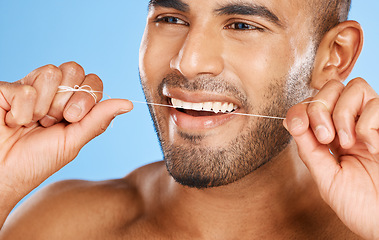 Image showing Wellness, dental and floss man cleaning teeth for good oral hygiene, health and tooth care. Clean, healthy and confident smile for flossing product advertising in blue studio closeup.