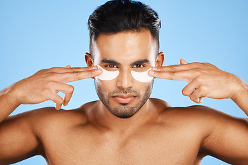 Image showing Man, eye patches and beauty for skincare, cosmetics or facial products against a blue studio background. Portrait of isolated male model in care for eyes applying patch for healthy skin or treatment