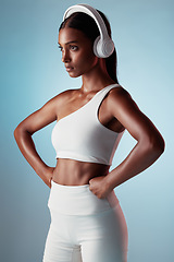 Image showing Fitness, studio and woman streaming music ready to start training, workout and body exercise in India, Mumbai. Focus, blue background and healthy girl athlete listening to radio or mindset podcast