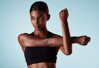 Image showing Fitness, studio and woman stretching shoulder and arms in a warm up to start training, workout and cardio exercise. Focus, wellness and healthy young sports girl relaxing her strong body muscles