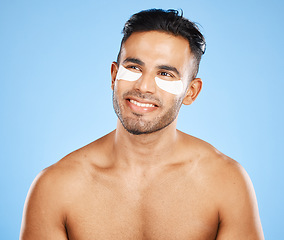 Image showing Skincare, eyes patch and man beauty, dermatology and body cosmetics of wellness, facial treatment or collagen eye care mask on studio blue background. Happy arab guy use healthy face for dark circles