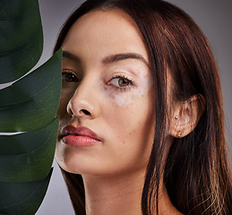 Image showing Beauty, leaf and woman with vitiligo in studio for wellness, skincare and luxury grooming on grey background mockup. Portrait, plant and face of dermatology model relax with natural facial product