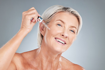 Image showing Senior woman, skincare and serum for beauty, cosmetics or anti aging treatment against a grey studio background. Happy elderly female applying oil with dropper and smile in satisfaction for skin