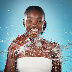 Image showing Beauty, splash and black woman in studio for cleaning, skincare and facial on blue background mockup. Water, face and portrait of girl model happy, relax and smile during grooming, hygiene and shower