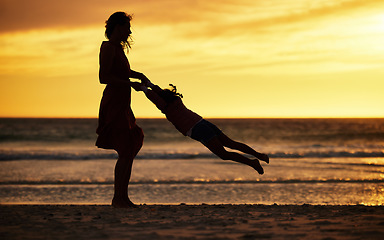 Image showing Family, silhouette and sunset at beach with mother swinging child against yellow sky with love, care and support on vacation in summer. Woman and kid by sea for travel fun, adventure and freedom