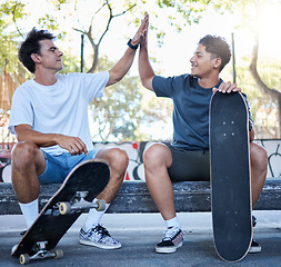 Image showing High five, skateboard and skater friends at city skatepark, young men sitting in park and celebration of achievement. Freedom, urban fun and happy gen z men hands celebrate skate trick goals