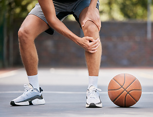 Image showing Pain, basketball and man with knee injury standing on outdoor court, holding leg. Sports, fitness and athlete with joint pain, injured and hurt in training, workout and game on basketball court