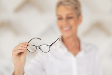 Image showing Vision, blur and woman holding glasses in an optometry store buying prescription lenses. Retail, optometrist and senior lady trying spectacles in optician, optical or eyewear shop for eye care.