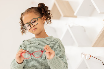 Image showing Glasses, options and children with a girl in an optometry store while shopping for prescription lenses. Kids, retail and vision with a female child customer looking at eyewear at the optometrist