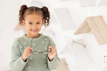 Image showing Girl, child and glasses for vision, shopping and buying spectacles in an optometry store. Retail, choice and eyewear for small kid choosing eyeglasses for eyesight and opthalmology
