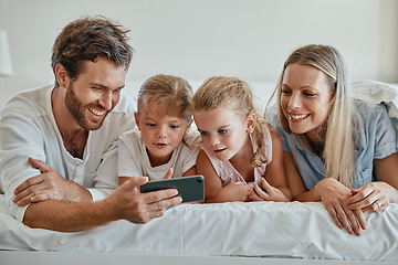 Image showing Happy family with kids, phone and lying on bed in home, mother, father and girl children watching video together. Love, fun and family with dad, mom and daughters on smartphone video call in bedroom.