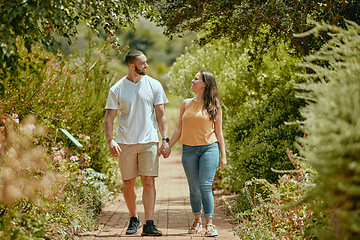 Image showing Couple, hand holding and nature park walking of people on a outdoor path with a smile. Happy girlfriend and boyfriend together showing love, care and commitment on a walk or hike feeling happiness