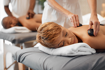 Image showing Spa, couple and massage for health and wellness while on bed for hot stone or rock therapy on back for zen, peace and relax. Man and woman customer in beauty salon for physical therapy and self care