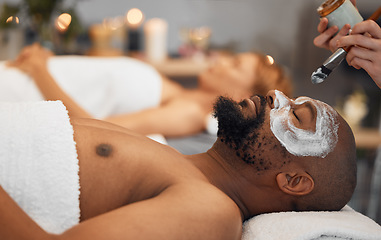 Image showing Skincare, wellness and black man getting a facial at a spa for relaxation, calm and satisfaction. Beauty, luxury treatment and couple massage at beauty salon together, skincare products on mans face