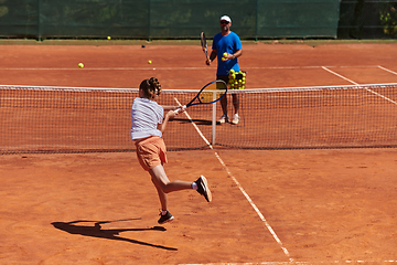 Image showing A professional tennis player and her coach training on a sunny day at the tennis court. Training and preparation of a professional tennis player