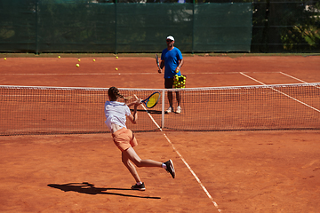 Image showing A professional tennis player and her coach training on a sunny day at the tennis court. Training and preparation of a professional tennis player