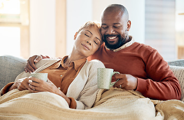 Image showing Black couple relax on sofa with coffee, blanket and smile on winter weekend morning in home. Peace, comfort and love, happy man and tired woman, cozy time on couch with drink in living room together.