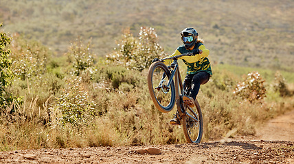 Image showing Mountain bike, sport and fitness outdoor with athlete doing stunt for extreme sports on dirt track in nature. Active with bicycle, safety helmet and biker exercise with training in desert.