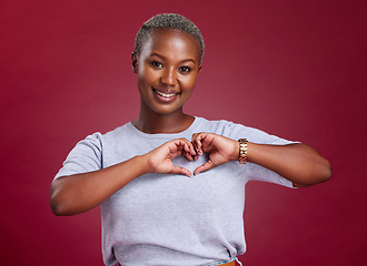 Image showing Hands, heart and love with a model black woman in studio on a red background to promote health or wellness. Portrait, smile and hand sign with a young female posing to endorse romance or cardio