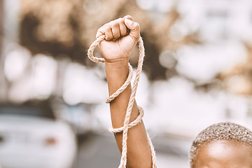 Image showing Hand, rope and fist protest slavery for freedom and human rights against an urban background. Activist, activism and rebellion against racism and change for civil, law and government rights