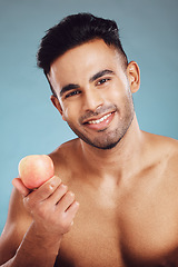 Image showing Apple, fitness and man in a studio portrait before eating healthy fruit on a vegan diet and wellness lifestyle. Nutrition, blue background and happy Indian model enjoying organic vitamins for a snack