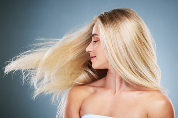 Image showing Hair care, healthy and blonde woman with keratin for growth, wellness and volume against a blue studio background. Luxury, happy and girl model with a smile for hair treatment, beauty and care