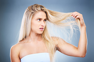 Image showing Upset, angry and annoyed woman with hair problem or style issue on a grey studio background. Damage, bad and expression of female unhappy with blonde hair loss for advertisement on a backdrop