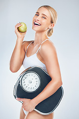 Image showing Apple, diet and woman with a scale to lose weight, training and smile against a grey studio background. Advertising, food and model excited about nutrition, fruit and balance for health of body